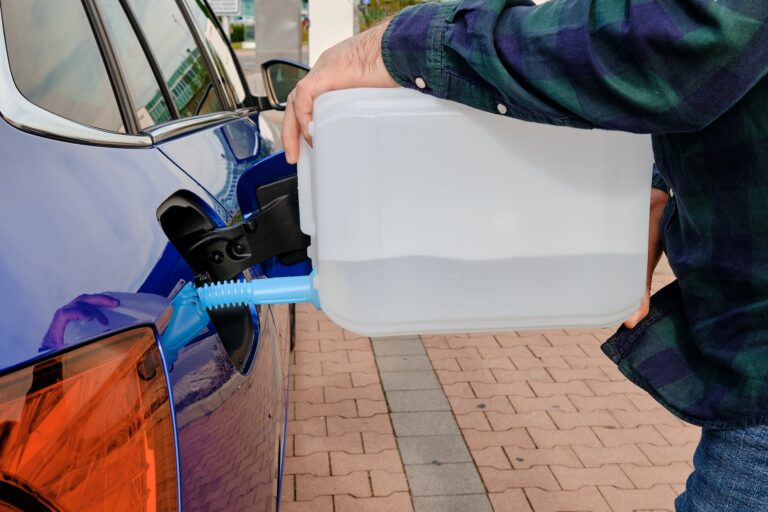 Man filling a diesel engine fluid from canister into the tank of blue car. Diesel exhaust fluid for